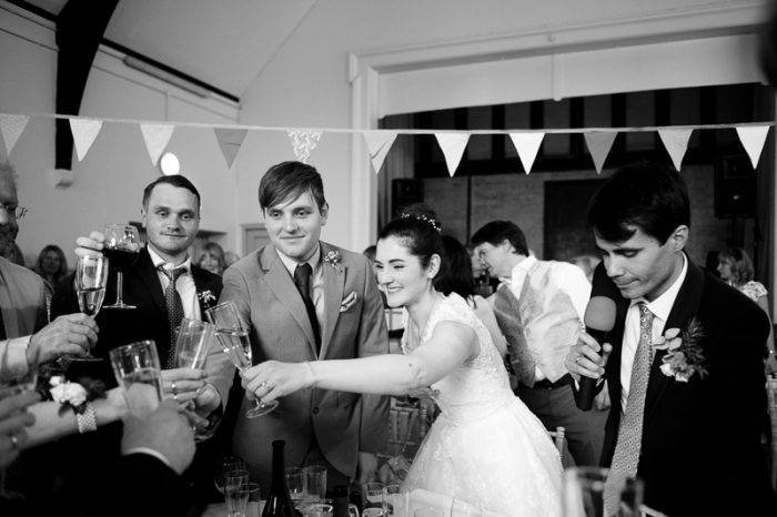 Bride raises a glass at Lyne Village Hall wedding